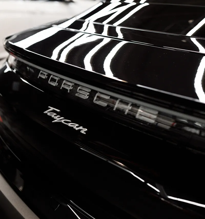 Close-up of the rear of a black Porsche Taycan showing the Porsche emblem and Taycan badge.