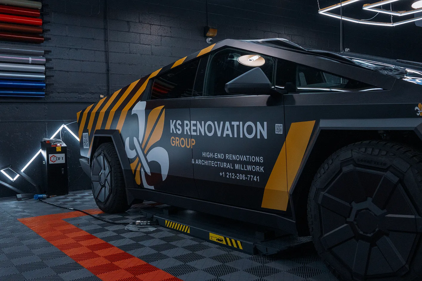 Side view of a black and orange car in a garage with KS Renovation Group logo and contact information on the door.